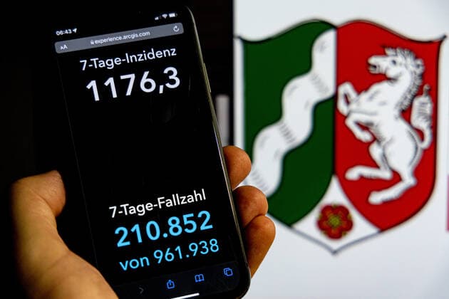 Coronavirus in Deutschland - Covid-19-Dashboard des Robert Koch-Institut DEU, Deutschland, Nordrhein-Westfalen 30.01.2022: Die 7-Tage-Inzidenz für das Bundesland (Fälle letzte 7 Tage 100.000 EW) wird auf einem iPhone angezeigt, im Hintergrund das Landeswappen