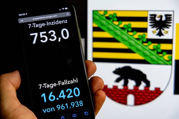 Coronavirus in Deutschland - Covid-19-Dashboard des Robert Koch-Institut DEU, Deutschland, Sachsen-Anhalt 30.01.2022: Die 7-Tage-Inzidenz für das Bundesland (Fälle letzte 7 Tage 100.000 EW) wird auf einem iPhone angezeigt, im Hintergrund das Landeswappen