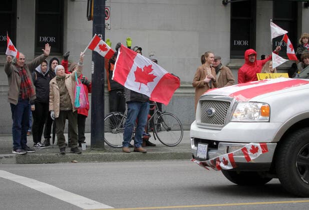 (220130) -- VANCOUVER, Jan. 30, 2022 -- Protestors wave flags as vehicles run along the street during a parade in support of Ottawa s Freedom Convoy trucker protest in downtown Vancouver, British Columbia, Canada, Jan. 29, 2022. Vehicles jammed downtown Vancouver streets Saturday to show their support of the Freedom Convoy of long-haul drivers to oppose the Canadian government s requirement that all cross-border essential workers, including truckers, must show proof of vaccination at a port of entry. (Photo by Xinhua) CANADA-VANCOUVER-FREEDOM CONVOY-SUPPORT-PARADE LiangxSen 