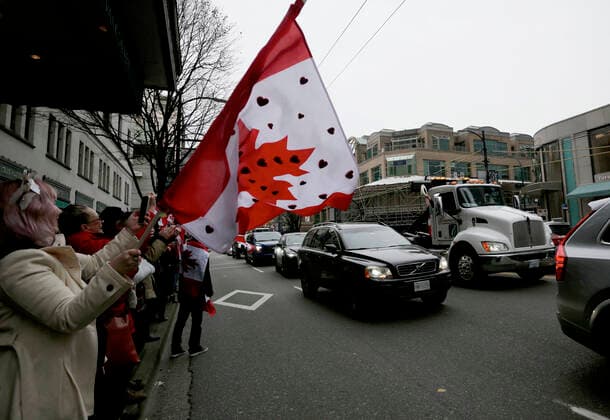 (220130) -- VANCOUVER, Jan. 30, 2022 -- Protestors wave flags as vehicles run along the street during a parade in support of Ottawa s Freedom Convoy trucker protest in downtown Vancouver, British Columbia, Canada, Jan. 29, 2022. Vehicles jammed downtown Vancouver streets Saturday to show their support of the Freedom Convoy of long-haul drivers to oppose the Canadian government s requirement that all cross-border essential workers, including truckers, must show proof of vaccination at a port of entry. (Photo by Xinhua) CANADA-VANCOUVER-FREEDOM CONVOY-SUPPORT-PARADE LiangxSen 