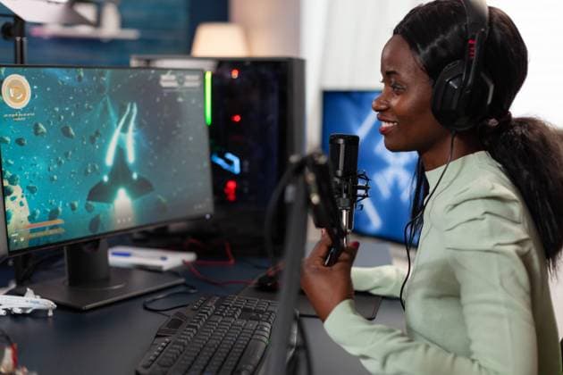 Professional woman gamer talking into microphone with players Professional woman gamer talking into microphone with players using streaming chat while playing space shooter videogames during online championship. Focused player using RBG gaming equipment Copyright: xPhotographer:xDragosxCondreax 44054458