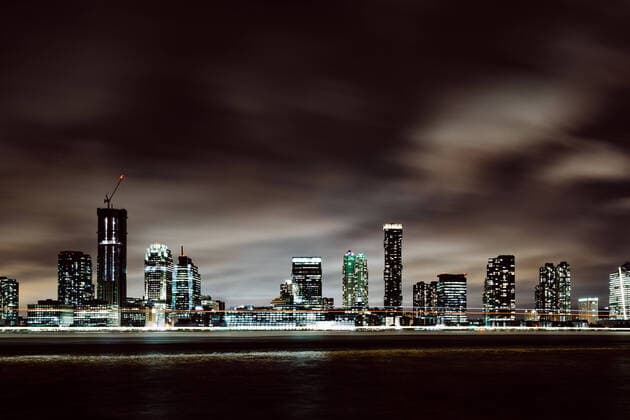 Blick auf Hochäuser in The Waterfront von der Battery Park City Esplanade bei Nacht mit Schiffslichtern, 21.08.2018 Jersey City The Waterfront New Jersey USA