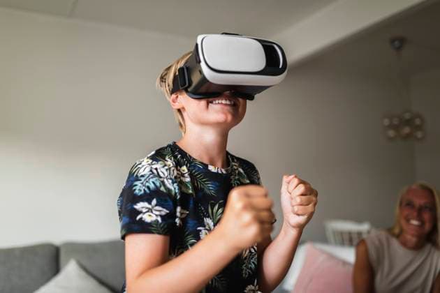 Smiling boy wearing virtual reality headset while mother sitting in background at home Sweden, Gothenburg, model released, property released Copyright: xMaskotx , MA91504
