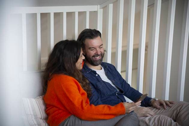 IMAGO Creative: Internationaler Frauenmonat, Gesundheit, Frauen in der Menopause Happy heterosexual couple using smart phone in bedroom Sweden, Stockholm, model released, property released Copyright: xMaskotx , MA92102