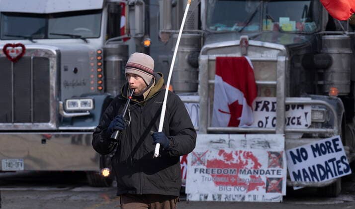 February 1, 2022, Ottawa, ON, Canada: A man blows on a horn as he walks past trucks parked in the downtown core on Tuesday, Feb. 1, 2022 in Ottawa. As organizers behind the demonstration that has seized the nation s capital say they are preparing to stick around even longer by distributing fuel and supplies to the trucks clogging up Ottawa streets, politicians at all levels of government are asking them to roll out. Ottawa Canada  - ZUMAc35_ 20220201_zaf_c35_031 Copyright: xAdrianxWyldx