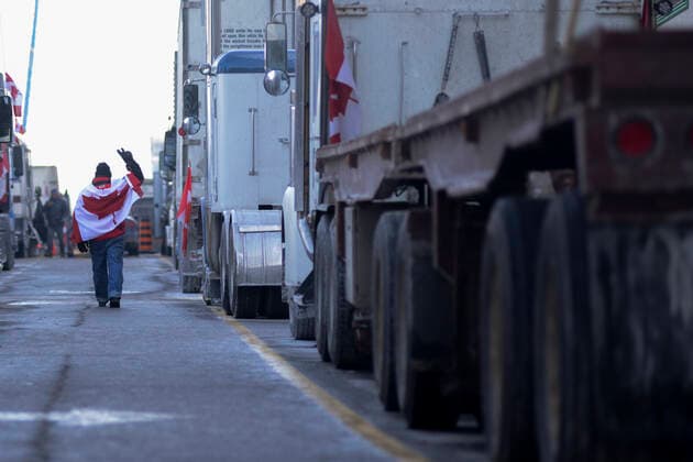 4th Day Of Trucker s Protest At Parliament Hill A supporter wrapped in Canadian flag showing victory sign to a driver during the 4th Day of Trucker s protest against the mandatory vaccine policy imposed on the Canadian truckers returning from USA to avoid a two week quarantine at Parliament Hill in Ottawa-Canada Ottawa Canada  Copyright: xArindamxShivaanix originalFilename: shivaanibahuguna-notitle220201_npRO7.jpg