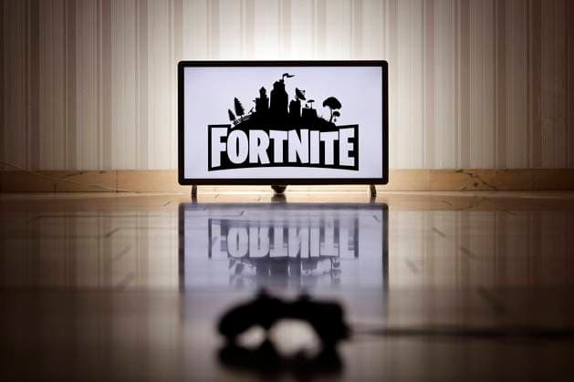 Das Logo des Survival-Shooters Fortnite auf einem Bildschirm, im Vordergrund ein Gaming-Controller. (Symbolbild, Symbolfoto) Köln, 01.02.2022 Foto:xC.xHardtx xFuturexImage