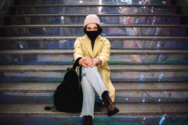Portrait of confident young woman wearing face mask sitting on steps CR_DMBE220203-885885-01 ,model released, Symbolfoto