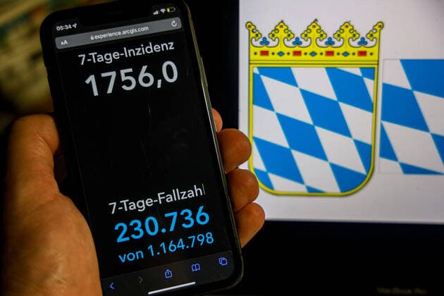 Coronavirus in Deutschland - Covid-19-Dashboard des Robert Koch-Institut DEU, Deutschland, Bayern 06.02.2022: Die 7-Tage-Inzidenz für das Bundesland (Fälle letzte 7 Tage 100.000 EW) wird auf einem iPhone angezeigt, im Hintergrund das Landeswappen