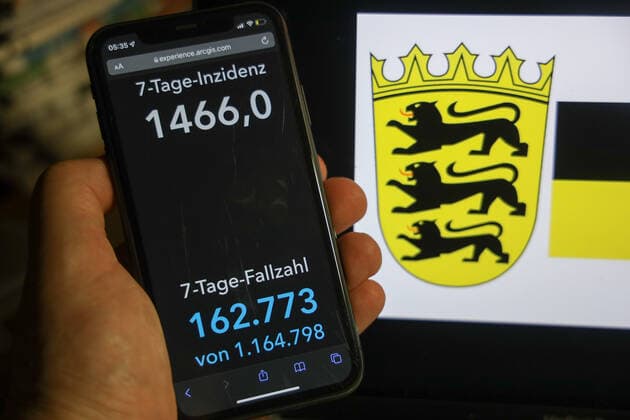 Coronavirus in Deutschland - Covid-19-Dashboard des Robert Koch-Institut DEU, Deutschland, Baden-Württemberg 06.02.2022: Die 7-Tage-Inzidenz für das Bundesland (Fälle letzte 7 Tage 100.000 EW) wird auf einem iPhone angezeigt, im Hintergrund das Landeswappen