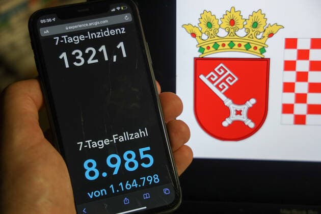 Coronavirus in Deutschland - Covid-19-Dashboard des Robert Koch-Institut DEU, Deutschland, Bremen 06.02.2022: Die 7-Tage-Inzidenz für das Bundesland (Fälle letzte 7 Tage 100.000 EW) wird auf einem iPhone angezeigt, im Hintergrund das Landeswappen