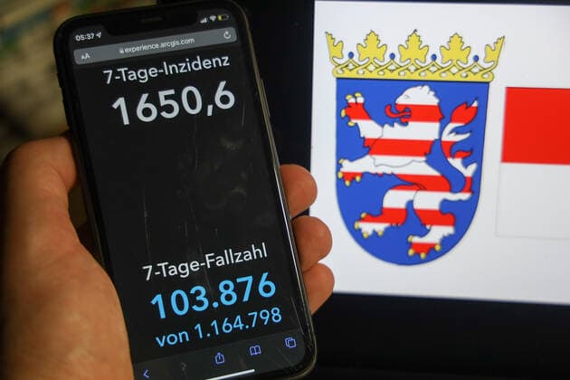 Coronavirus in Deutschland - Covid-19-Dashboard des Robert Koch-Institut DEU, Deutschland, Hessen 06.02.2022: Die 7-Tage-Inzidenz für das Bundesland (Fälle letzte 7 Tage 100.000 EW) wird auf einem iPhone angezeigt, im Hintergrund das Landeswappen
