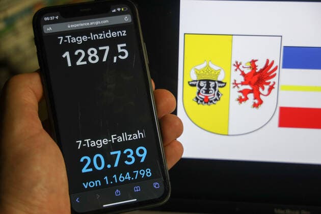 Coronavirus in Deutschland - Covid-19-Dashboard des Robert Koch-Institut DEU, Deutschland, Mecklenburg-Vorpommern 06.02.2022: Die 7-Tage-Inzidenz für das Bundesland (Fälle letzte 7 Tage 100.000 EW) wird auf einem iPhone angezeigt, im Hintergrund das Landeswappen