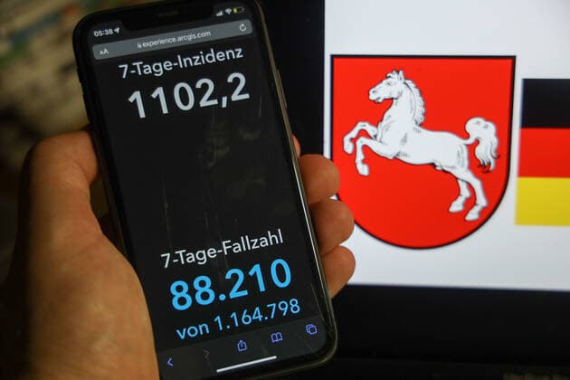 Coronavirus in Deutschland - Covid-19-Dashboard des Robert Koch-Institut DEU, Deutschland, Niedersachsen 06.02.2022: Die 7-Tage-Inzidenz für das Bundesland (Fälle letzte 7 Tage 100.000 EW) wird auf einem iPhone angezeigt, im Hintergrund das Landeswappen