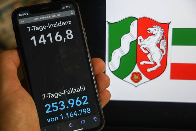 Coronavirus in Deutschland - Covid-19-Dashboard des Robert Koch-Institut DEU, Deutschland, Nordhrhein-Westfalen 06.02.2022: Die 7-Tage-Inzidenz für das Bundesland (Fälle letzte 7 Tage 100.000 EW) wird auf einem iPhone angezeigt, im Hintergrund das Landeswappen
