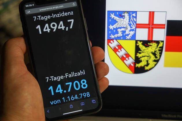 Coronavirus in Deutschland - Covid-19-Dashboard des Robert Koch-Institut DEU, Deutschland, Saarland 06.02.2022: Die 7-Tage-Inzidenz für das Bundesland (Fälle letzte 7 Tage 100.000 EW) wird auf einem iPhone angezeigt, im Hintergrund das Landeswappen