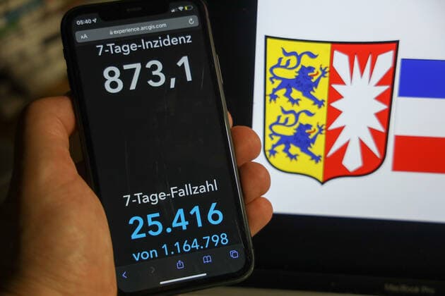 Coronavirus in Deutschland - Covid-19-Dashboard des Robert Koch-Institut DEU, Deutschland, Schleswig-Holstein 06.02.2022: Die 7-Tage-Inzidenz für das Bundesland (Fälle letzte 7 Tage 100.000 EW) wird auf einem iPhone angezeigt, im Hintergrund das Landeswappen