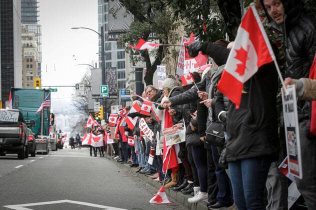 (220206) -- VANCOUVER, Feb. 6, 2022 -- People wave flags as vehicles participate in a convoy to support the truckers against COVID-19 vaccine mandate in downtown Vancouver, Canada, Feb. 5, 2022. In solidarity with protesters in downtown Ottawa, anti COVID-19 vaccine mandates and restrictions supporters in Vancouver took part in vehicle convoys and rallies protesting against Canadian government s vaccine mandate for essential workers crossing the Canada-U.S. border. (Photo by Xinhua) CANADA-VANCOUVER-COVID-19-CONVOY PROTEST LiangxSen 