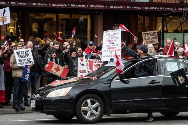 February 5, 2022, Vancouver, British Columbia, Canada: A driver gets out of his car to cheer on fellow protesters against COVID-19 safety mandates in downtown Vancouver Feb. 5. A convoy of hundreds of vehicles travelled from several nearby municipalities to show their support for the so-called Freedom Convoy of truckers, who brought their protest of mandated vaccines for travel to and from the United States to the nationÃ¢â‚¬â ¢s capital, Ottawa, Ontario, bringing parts of the city to a stand still for the past five days. Vancouver Canada - ZUMAb217 20220205_zip_b217_002 Copyright: xQuinnxBenderx