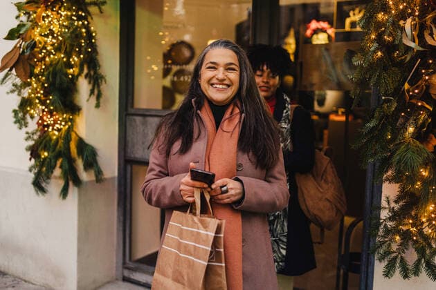 Happy diverse women walking out of decorated store with purchases after shopping during Christmas time, Model released JakeJakab_EliAlicia_72.jpg Copyright: xJakexJakabx MR