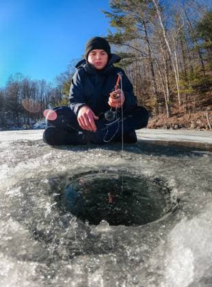 Teen boy ice fishing on a frozen lake on a cold winter day in Canada. Buck Lake, Ontario, Canada CR_DOHO220209F-919255-01 ,model released, Symbolfoto