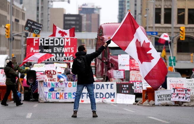 February 11, 2022, Ottawa, ON, CAN: A protester waves a Canadian flag in front of parked vehicles on Rideau Street on the 15th day of a protest against COVID-19 measures that has grown into a broader anti-government protest, in Ottawa, Friday, Feb. 11, 2022. Ottawa CAN  - ZUMAc35_ 20220211_zaf_c35_167 Copyright: xJustinxTangx