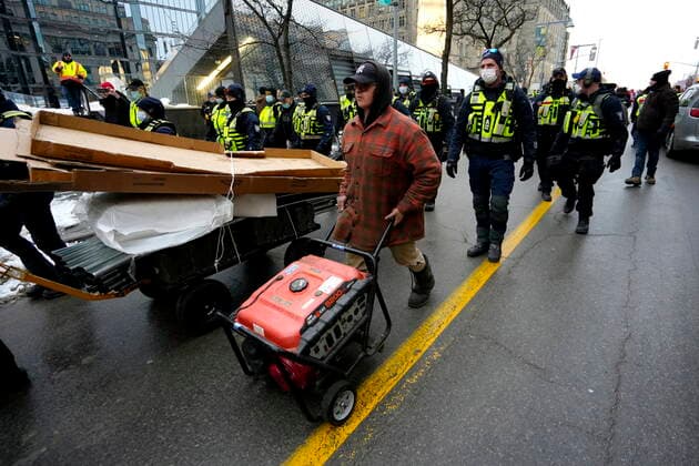 February 11, 2022, Ottawa, ON, CAN: Police escort a protester wheeling a generator down Bank Street after they intervened to stop a group from building a tent structure on Wellington Street, on the 15th day of a protest against COVID-19 measures that has grown into a broader anti-government protest, in Ottawa, Friday, Feb. 11, 2022. Ottawa CAN  - ZUMAc35_ 20220211_zaf_c35_168 Copyright: xJustinxTangx
