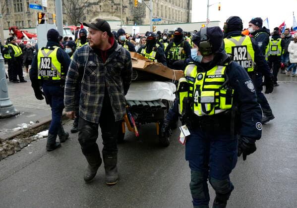 February 11, 2022, Ottawa, ON, CAN: Police escort a protester wheeling a cart of building supplies down Bank Street after they intervened to stop a group from building a tent structure on Wellington Street, on the 15th day of a protest against COVID-19 measures that has grown into a broader anti-government protest, in Ottawa, Friday, Feb. 11, 2022. Ottawa CAN  - ZUMAc35_ 20220211_zaf_c35_170 Copyright: xJustinxTangx