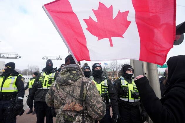 February 12, 2022, Windsor, ON, CANADA: A protester yells at police officers as demonstrators prepare to leave in advance of police enforcing an injunction against their demonstration, which has blocked traffic across the Ambassador Bridge by protesters against COVID-19 restrictions, in Windsor, Ont., Saturday, Feb. 12, 2022. Windsor CANADA  - ZUMAc35_ 20220212_zaf_c35_105 Copyright: xNathanxDenettex