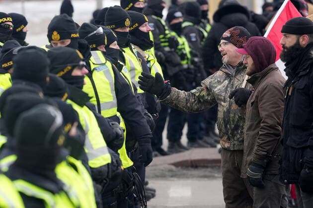 February 12, 2022, Windsor, ON, CANADA: A protester attempts to speak with police officers as they enforce an injunction against their demonstration, which has blocked traffic across the Ambassador Bridge by protesters against COVID-19 restrictions, in Windsor, Ont., Saturday, Feb. 12, 2022. Windsor CANADA  - ZUMAc35_ 20220212_zaf_c35_128 Copyright: xNathanxDenettex