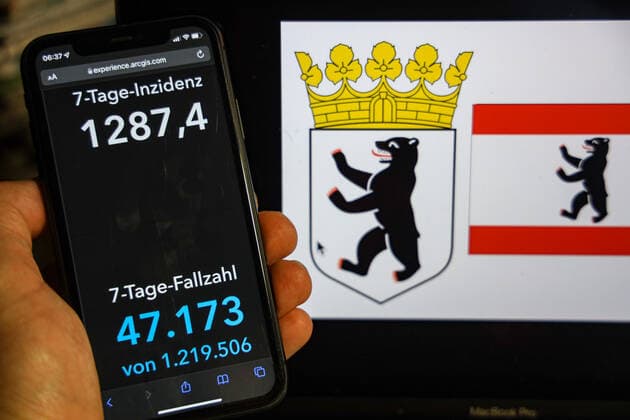 Coronavirus in Deutschland - Covid-19-Dashboard des Robert Koch-Institut DEU, Deutschland, Berlin 13.02.2022: Die 7-Tage-Inzidenz für das Bundesland (Fälle letzte 7 Tage 100.000 EW) wird auf einem iPhone angezeigt, im Hintergrund das Landeswappen