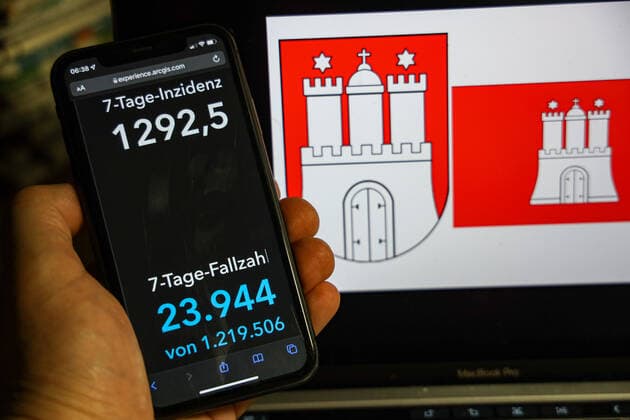 Coronavirus in Deutschland - Covid-19-Dashboard des Robert Koch-Institut DEU, Deutschland, Hamburg 13.02.2022: Die 7-Tage-Inzidenz für das Bundesland (Fälle letzte 7 Tage 100.000 EW) wird auf einem iPhone angezeigt, im Hintergrund das Landeswappen