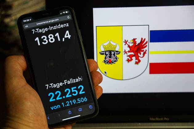 Coronavirus in Deutschland - Covid-19-Dashboard des Robert Koch-Institut DEU, Deutschland, Mecklenburg-Vorpommern 13.02.2022: Die 7-Tage-Inzidenz für das Bundesland (Fälle letzte 7 Tage 100.000 EW) wird auf einem iPhone angezeigt, im Hintergrund das Landeswappen