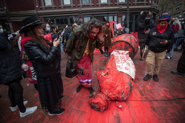 February 14, 2022, VANCOUVER, BC, CANADA: A person spits on the Gassy Jack statue after it was toppled and covered in red paint during the annual Women s Memorial March, in Vancouver, on Monday, February 14, 2022. The statue is a monument to Gassy Jack Deighton, a Vancouver saloon owner in the 1860s, whom Vancouver s Gastown neighbourhood is named after. The march is held to honour missing and murdered women and girls from the community with stops along the way to commemorate where women were last seen or found. VANCOUVER CANADA  - ZUMAc35_ 20220214_zaf_c35_172 Copyright: xDarrylxDyckx