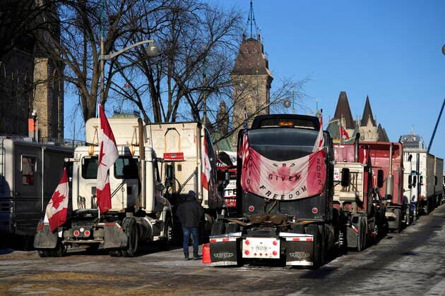 February 14, 2022, Ottawa, ON, CAN: A person walks among trucks as Wellington Street is lined with trucks once again after city officials negotiated to move some trucks towards Parliament and away from downtown residences, on the 18th day of a protest against COVID-19 measures that has grown into a broader anti-government protest, in Ottawa, on Monday, Feb. 14, 2022. Ottawa CAN  - ZUMAc35_ 20220214_zaf_c35_174 Copyright: xJustinxTangx