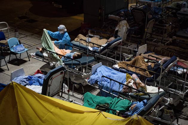 February 16, 2022, Hong Kong, China: A health worker wearing a Personal Protective Equipment suit (PPE) seen helping a suspected covid-19 patient on his bed..Hong Kong is struggling to contain the outbreak of Covid-19, with most of hospitals running over their capacity. Patients on hospital beds lined up outside A&E departments of the Caritas Medical Centre waiting to get into the hospital. Hong Kong China - ZUMAs197 20220216_zaa_s197_076 Copyright: xDominicxChiux