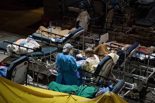 February 16, 2022, Hong Kong, China: A health worker wearing a Personal Protective Equipment suit (PPE) seen helping a a suspected covid-19 patient on her bed..Hong Kong is struggling to contain the outbreak of Covid-19, with most of hospitals running over their capacity. Patients on hospital beds lined up outside A&E departments of the Caritas Medical Centre waiting to get into the hospital. Hong Kong China - ZUMAs197 20220216_zaa_s197_078 Copyright: xDominicxChiux