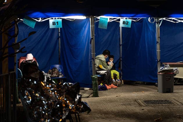 Hong Kong s COVID-19 Infections Soar On February 16, 2022, in a temporary shelter outside Caritas Medical Center in Hong Kong, China, a patient lies in a hospital bed waiting for medical treatment. The temperature drops at night, the patient is put on thermal insulation products, and a father feeds his son. The Food and Health Bureau confirmed a new record of 4,285 infections, while 7,000 people initially tested positive, a near-record high. At least 12,000 infected people are waiting to be admitted to hospitals as COVID-19 cases overwhelm the public health system. Hong Kong China  Copyright: xLeungxManxHeix originalFilename: manhei-notitle220216_npWA9.jpg
