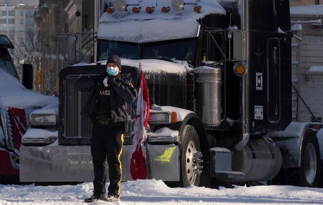 Kanada, Protest gegen Corona-Maßnahmen in Ottawa - Polizei beginnt mit Räumung von LKW-Blockade February 18, 2022, Ottawa, ON, Canada: A police officer watches as a truck drives away leaving the protest site, Friday, Feb. 18, 2022 in Ottawa. Ottawa Canada  - ZUMAc35_ 20220218_zaf_c35_082 Copyright: xAdrianxWyldx