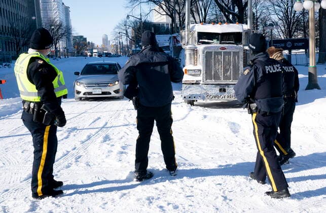 Kanada, Protest gegen Corona-Maßnahmen in Ottawa - Polizei beginnt mit Räumung von LKW-Blockade February 18, 2022, Ottawa, ON, Canada: Police officers keep an eye on a vehicle as it approaches next to trucks parked as part of the protests, Friday, Feb. 18, 2022 in Ottawa. Ottawa Canada  - ZUMAc35_ 20220218_zaf_c35_085 Copyright: xAdrianxWyldx