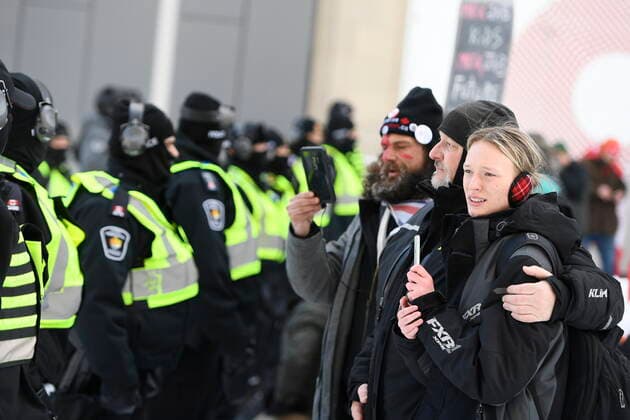 Kanada, Protest gegen Corona-Maßnahmen in Ottawa - Polizei beginnt mit Räumung von LKW-Blockade February 18, 2022, Ottawa, ON, CAN: Protesters embrace in front of police officers on Rideau Street near the truck blockade in Ottawa, on Friday, Feb. 18, 2022. Ottawa CAN  - ZUMAc35_ 20220218_zaf_c35_107 Copyright: xJustinxTangx