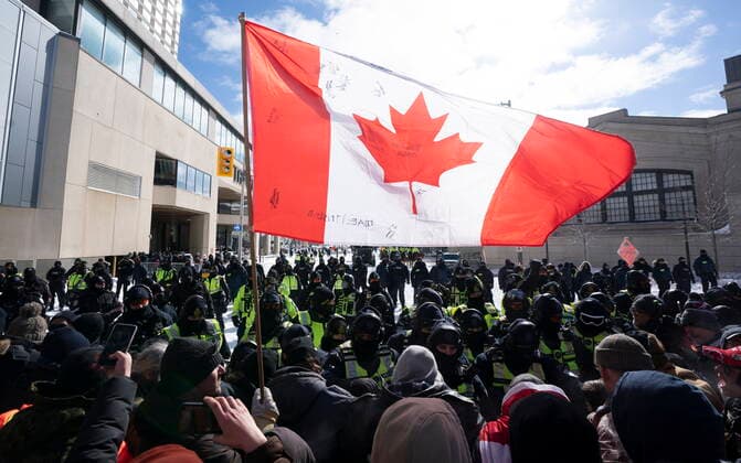 Kanada, Protest gegen Corona-Maßnahmen in Ottawa - Polizei beginnt mit Räumung von LKW-Blockade February 18, 2022, Ottawa, ON, Canada: A Canadian flag is held up by a protester as police move the line up as they work to end a protest, which started in opposition to mandatory COVID-19 vaccine mandates and grew into a broader anti-government demonstration and occupation, in Ottawa, Friday, Feb. 18, 2022. Ottawa Canada  - ZUMAc35_ 20220218_zaf_c35_132 Copyright: xAdrianxWyldx