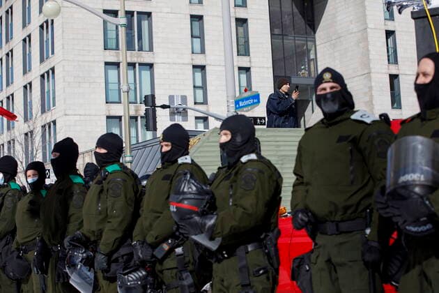 Kanada, Protest gegen Corona-Maßnahmen in Ottawa - Polizei beginnt mit Räumung von LKW-Blockade February 18, 2022, OTTAWA, ON, CANADA: Police form a line as a protester films while authorities move to end a protest against COVID-19 measures that has grown into a broader anti-government protest and occupation, in Ottawa, Friday, Feb. 18, 2022. OTTAWA CANADA  - ZUMAc35_ 20220218_zaf_c35_145 Copyright: xColexBurstonx
