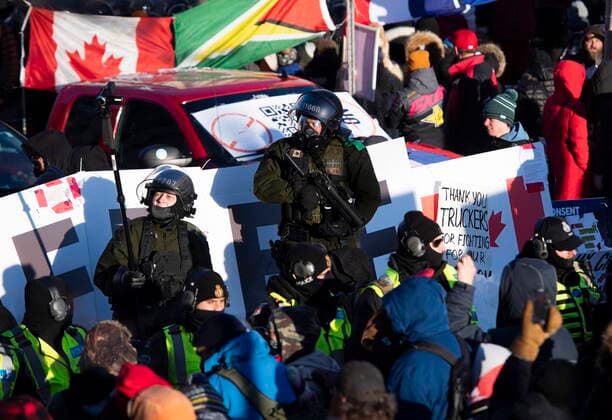 February 18, 2022, Ottawa, ON, CAN: A Surete du Quebec police officer holds a crowd control weapon while another records video on a monopod, as police form a line at an enclosure on Rideau Street as they work to end an ongoing protest against COVID-19 measures that has grown into a broader anti-government protest, on its 22nd day, in Ottawa, on Friday, Feb. 18, 2022. Ottawa CAN  - ZUMAc35_ 20220218_zaf_c35_248 Copyright: xJustinxTangx