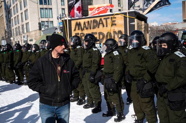 February 18, 2022, Ottawa, ON, CAN: A protester looks at Surete du Quebec police officers forming a line on Rideau Street as police work to end an ongoing protest against COVID-19 measures that has grown into a broader anti-government protest, on its 22nd day, in Ottawa, on Friday, Feb. 18, 2022. Ottawa CAN  - ZUMAc35_ 20220218_zaf_c35_249 Copyright: xJustinxTangx