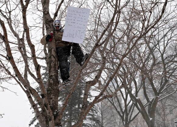 February 19, 2022, QUEBEC, PQ, Canada: A man sits on a branch as hundreds of people demonstrate against COVID-19 measures in front of the legislature in Quebec City, Saturday, Feb. 19, 2022. QUEBEC Canada  - ZUMAc35_ 20220219_zaf_c35_097 Copyright: xJacquesxBoissinotx