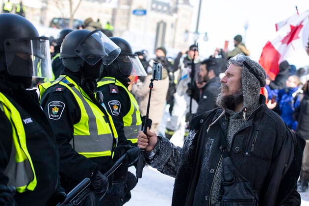 February 19, 2022, Ottawa, ON, Canada: A protester records a police line with their phone as police move in to clear downtown Ottawa near Parliament Hill of protesters after weeks of demonstrations on Saturday, Feb. 19, 2022. Police arrested scores of demonstrators and towed away vehicles Friday in Canada s besieged capital, and a stream of trucks started leaving under the pressure, raising authorities hopes for an end to the three-week protest against the country s COVID-19 restrictions. Ottawa Canada  - ZUMAc35_ 20220219_zaf_c35_141 Copyright: xJustinxTangx