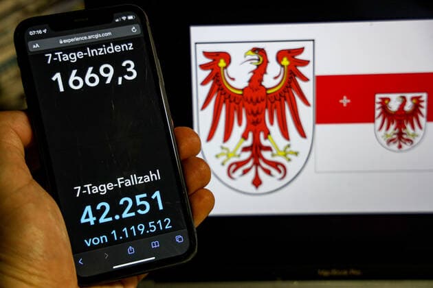 Coronavirus in Germany Covid 19 Dashboard of the Robert Koch Institute DEU, Germany, Brandenburg 20 02 2022 The 7-day incidence for the state Cases last 7 days 100 000 p.e. is displayed on an iPhone, with the state coat of arms in the background.