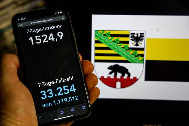 Coronavirus in Germany Covid 19 Dashboard of the Robert Koch Institute DEU, Germany, Saxony Anhalt 20 02 2022 The 7-day incidence for the state Cases last 7 days 100 000 p.e. is displayed on an iPhone, with the state coat of arms in the background.