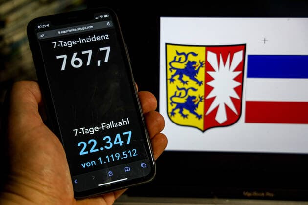 Coronavirus in Germany Covid 19 Dashboard of the Robert Koch Institute DEU, Germany, Schleswig Holstein 20 02 2022 The 7-day incidence for the state Cases last 7 days 100 000 p.e. is displayed on an iPhone, with the state coat of arms in the background.